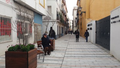Un vecino habla por teléfono desde uno de los nuevos bancos de madera instalados en la recien remodelada calle Baños
