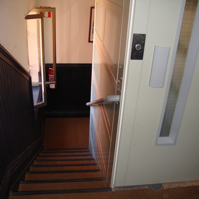 Imagen de un ascensor junto a las escaleras de un bloque de viviendas