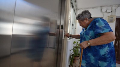 Una señora accede a un ascensor en un edificio de viviendas