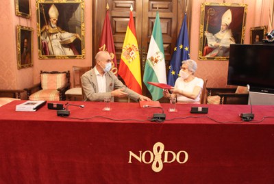El delegado de Hábitat Urbano y la presidenta de la comunidad de propietarios de uno de los bloques subvencionados se intercambian los convenios para su firma