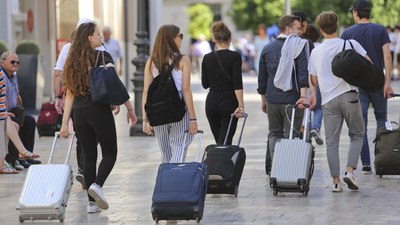 Un grupo de turistas caminan por una calle de Sevilla con su equipaje