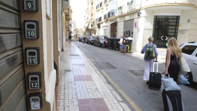 Unos turistas pasan por delante de la entrada a unas viviendas de uso turístico