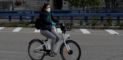 Una jóven circula por una calle en una bicicleta eléctrica