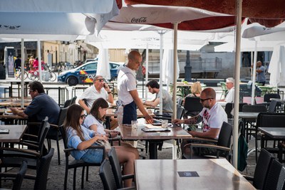 Un camarero atiende a unos clientes en una terraza de veladores