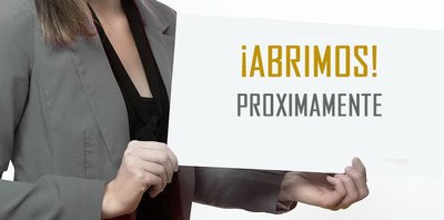 Una empresaria sostiene entre sus manos un cartel con la frase "abrimos próximamente"