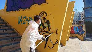 Un operario del Ayuntamiento retira unas pintadas sobre un paramento en la vía pública
