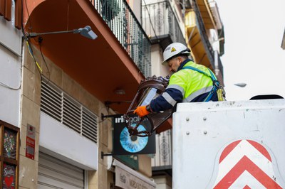 Un operario coloca un farol fernandino en la calle Sierpes tras desmontar el brazo mural de chapa anterior